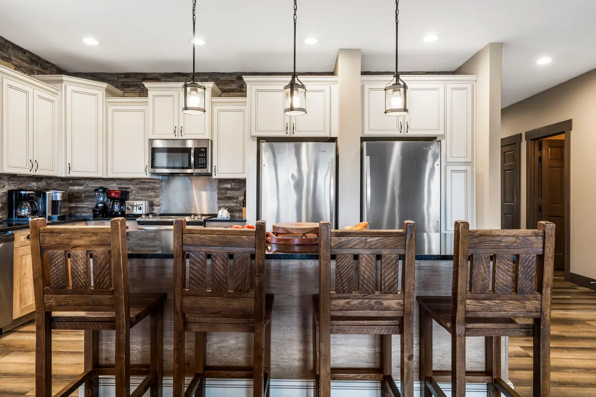 A modern and inviting kitchen with a central island, bar stools, sleek appliances, and warm cabinetry. The layout encourages both meal prep and social interaction, supporting the needs of large groups and culinary enthusiasts.