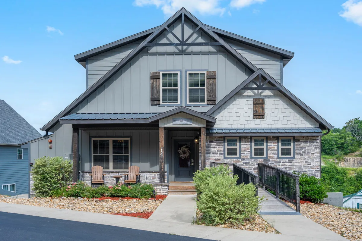 This image features the lodge's front porch with a stone facade, wooden shutters, and a landscaped garden. The porch looks inviting, with space for relaxing and enjoying the surrounding nature, emphasizing the welcoming exterior and easy access to outdoor spaces.